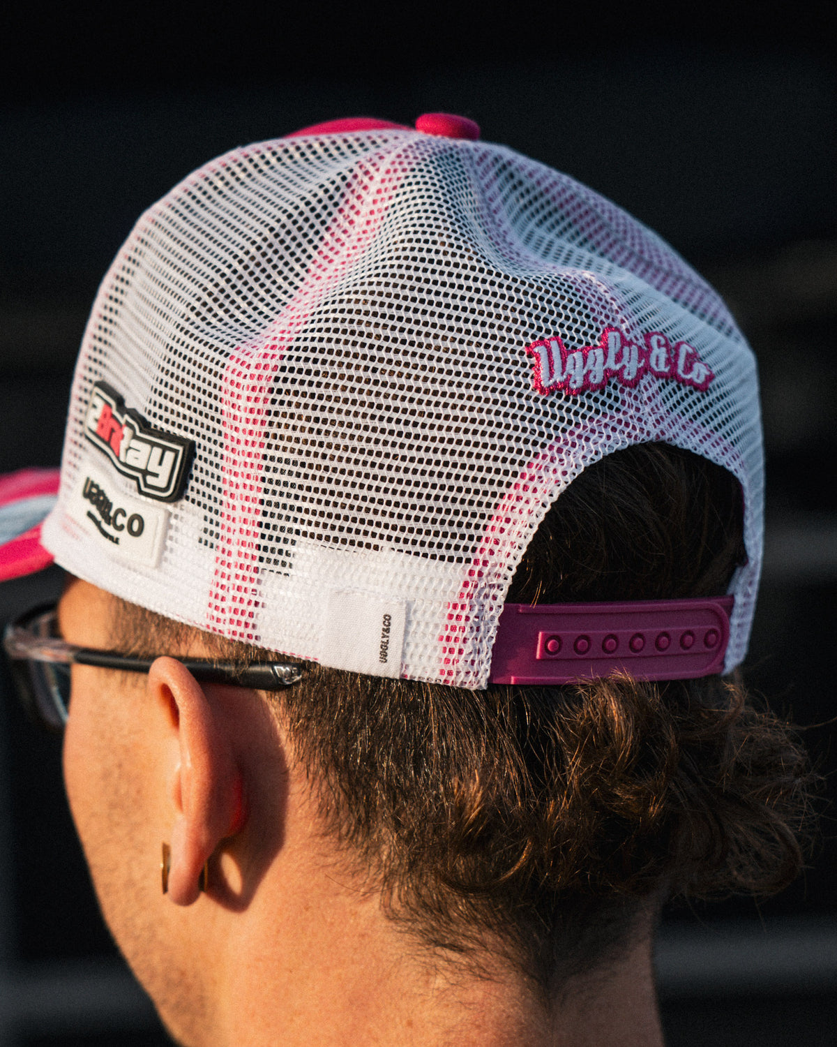 photo showing the mesh and closing of pink and white trucker hat worn by Bradley Ray