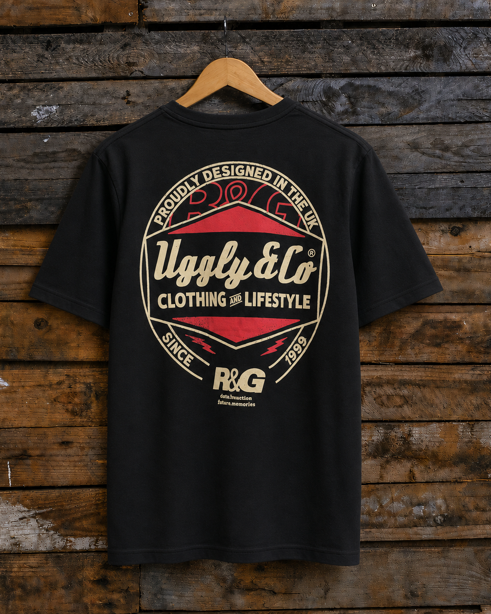 Rear view of a black t-shirt with a red and gold R&G Since 1999 logo on a wooden background