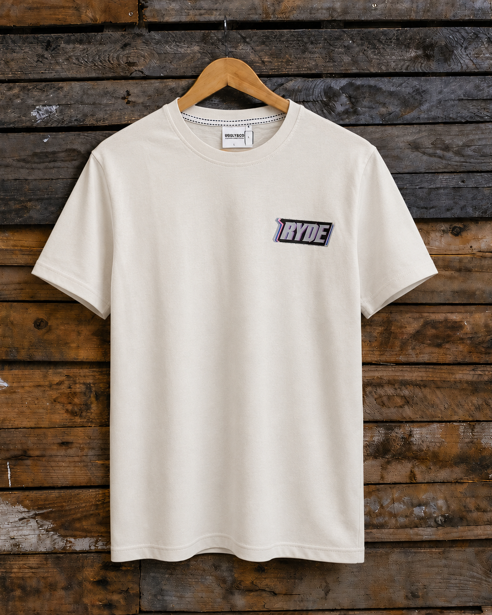 Front view of an Uggly & Co white t-shirt with Kyle Ryde inspired Ryde graphic on a wooden background