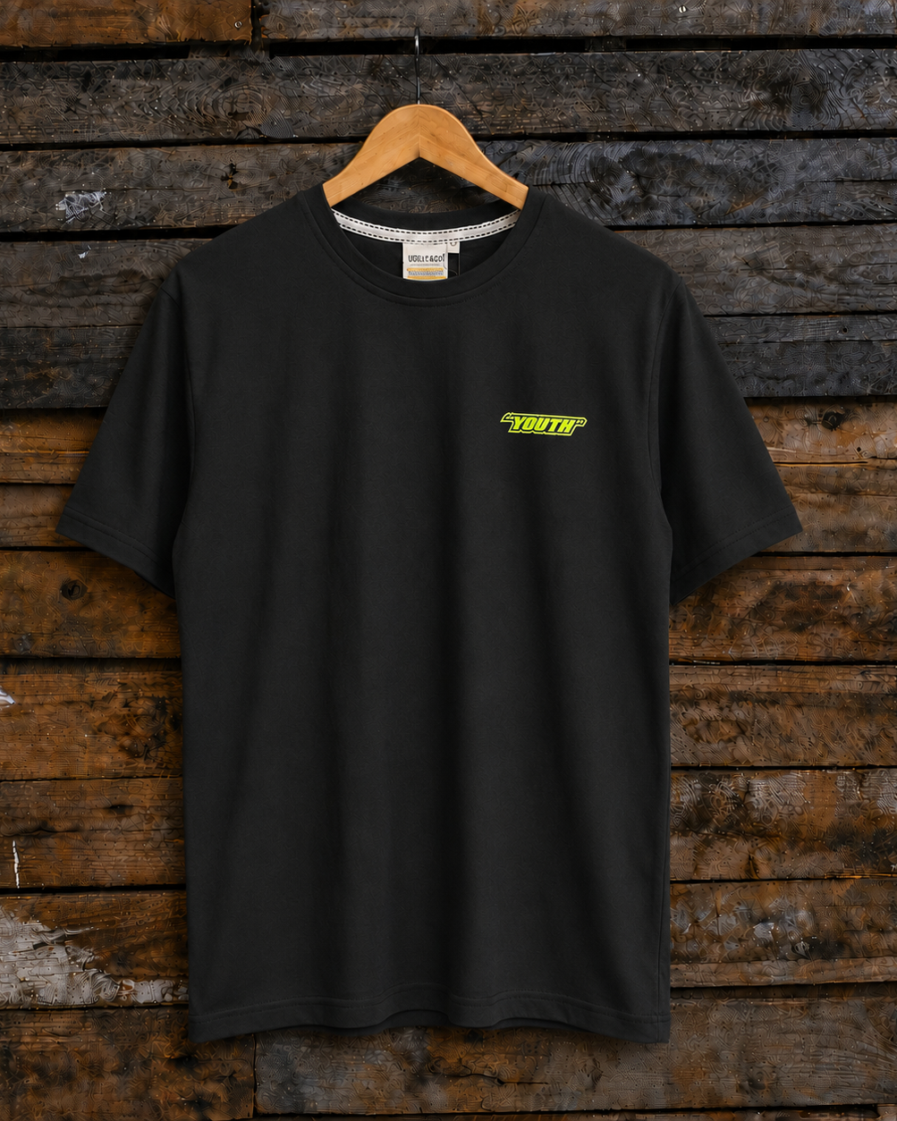 Front view of a black t-shirt with a lime green 'Youth' graphic on the chest hanging on a rustic wooden wall.