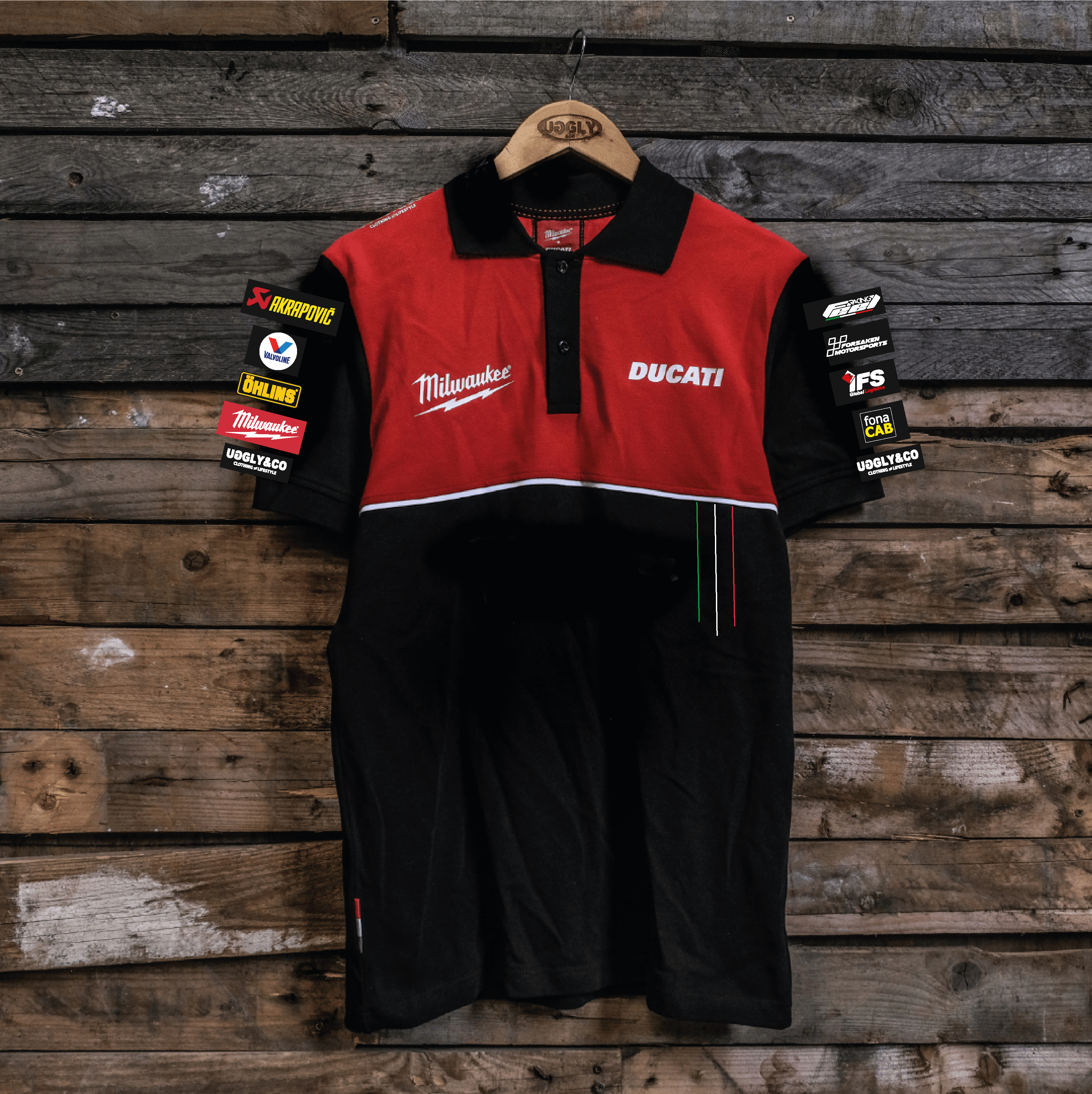 A polo shirt with the Ducati and Milwaukee Tools logos, featuring a black lower half and a red upper torso, displayed on a wooden background.