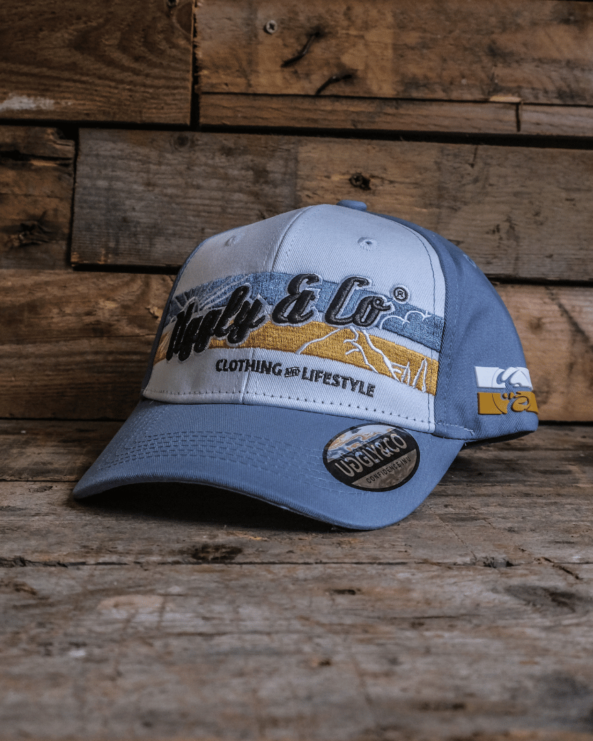 A sky blue and white vintage cap with embroidered design elements and the Uggly&Co brand logo on the front.