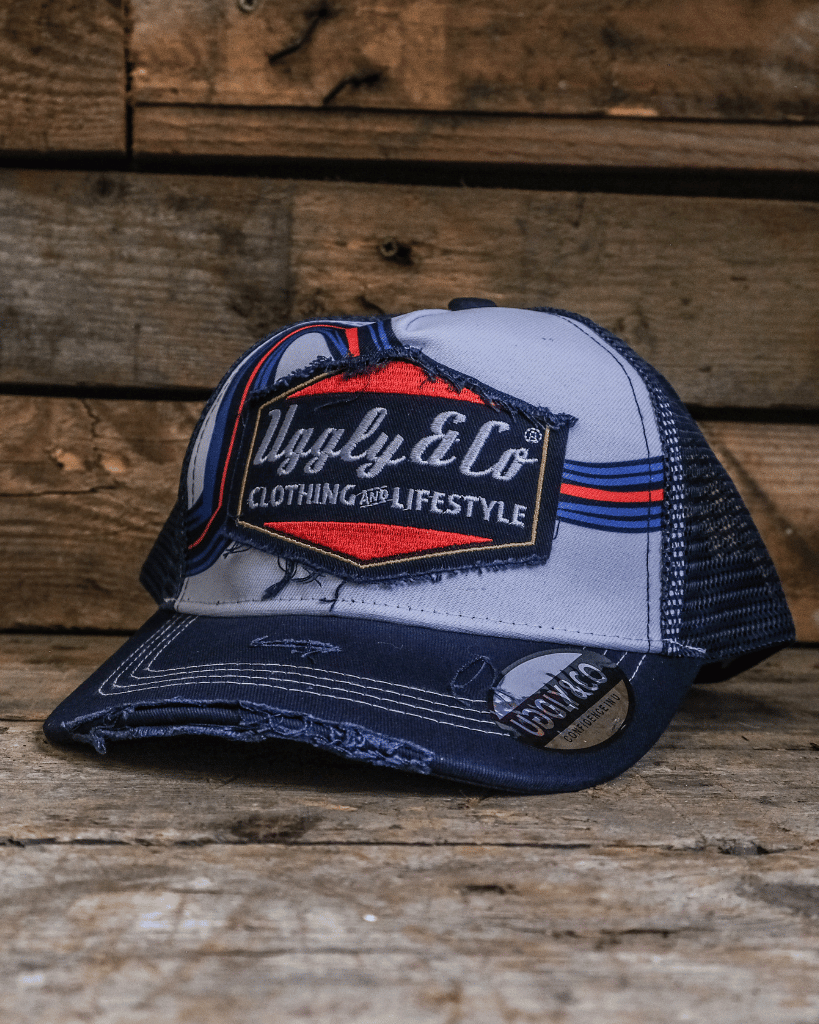 White, red and blue trucker hat with a diamond Uggly&Co logo on a wooden background