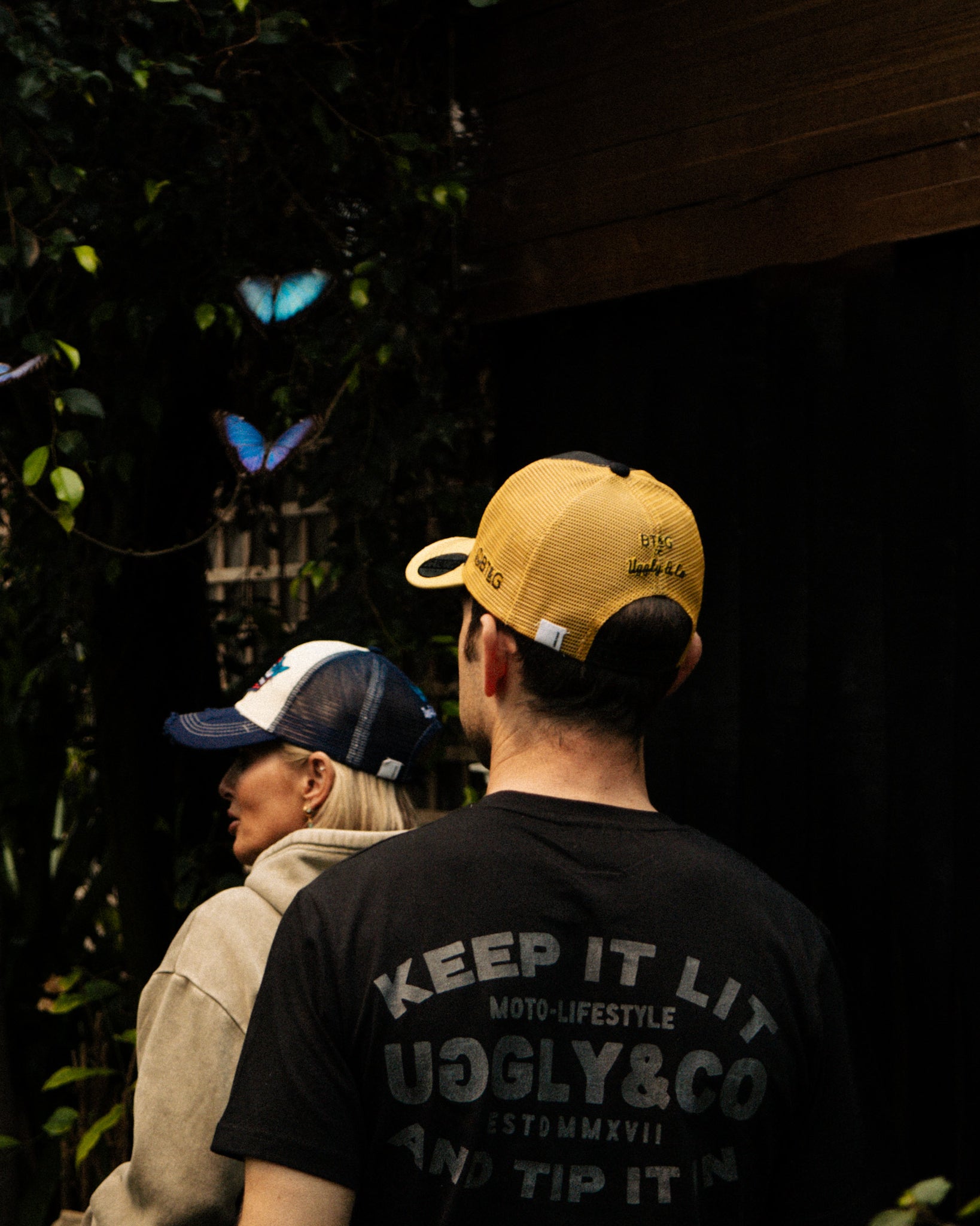 Sylvain Guintoli and wife in the butchers tap trucker hat stood in forest with butterflies