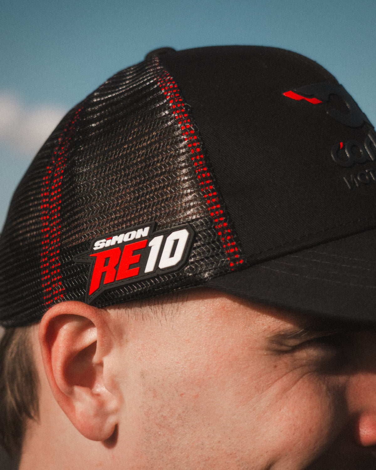 Side profile of the Carl Cox x Alpha Racing & Simon Reid Trucker Hat, showcasing its Simon Reid logo