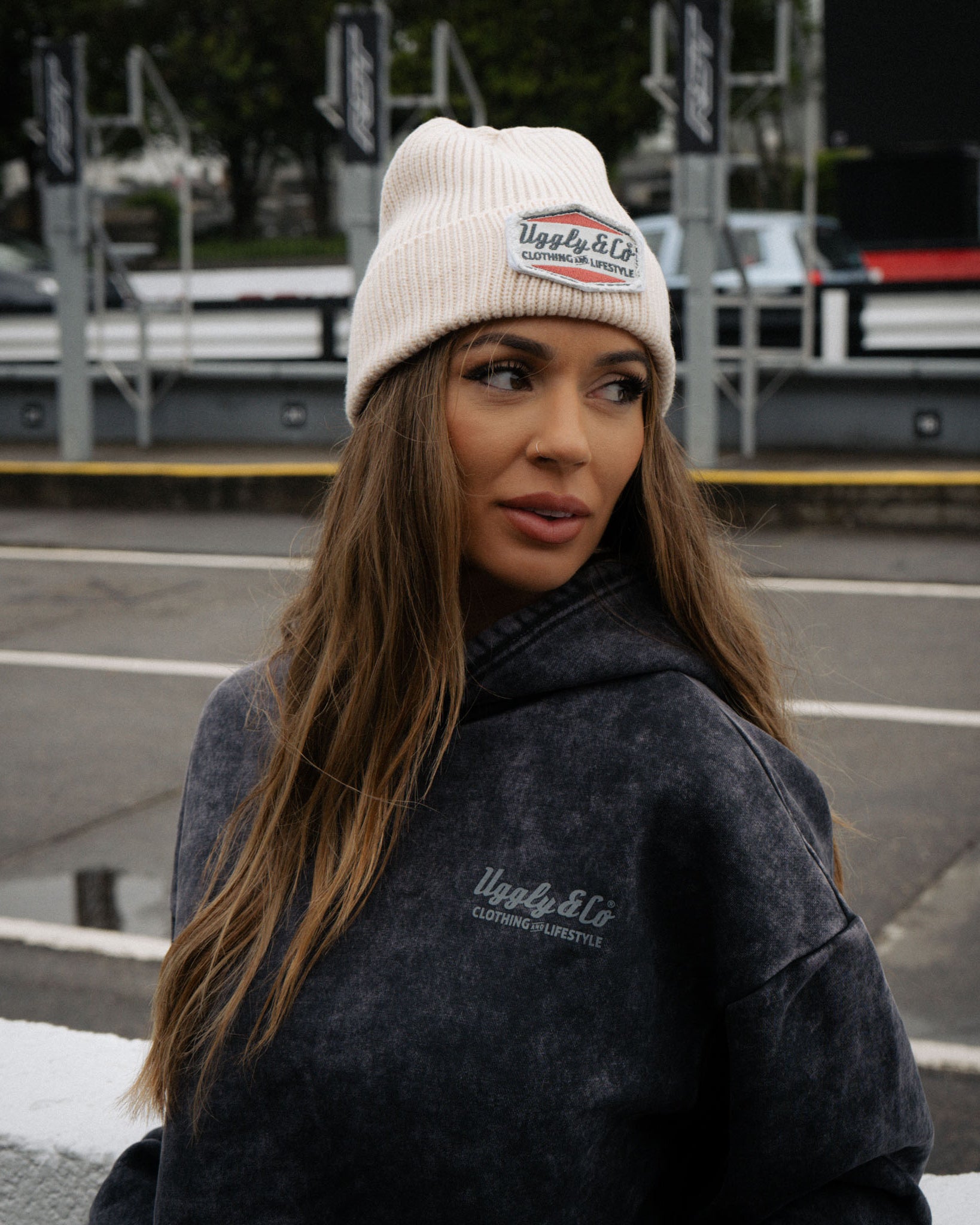Close lifestyle shot of a girl wearing the beige Diamond beanie in pit lane