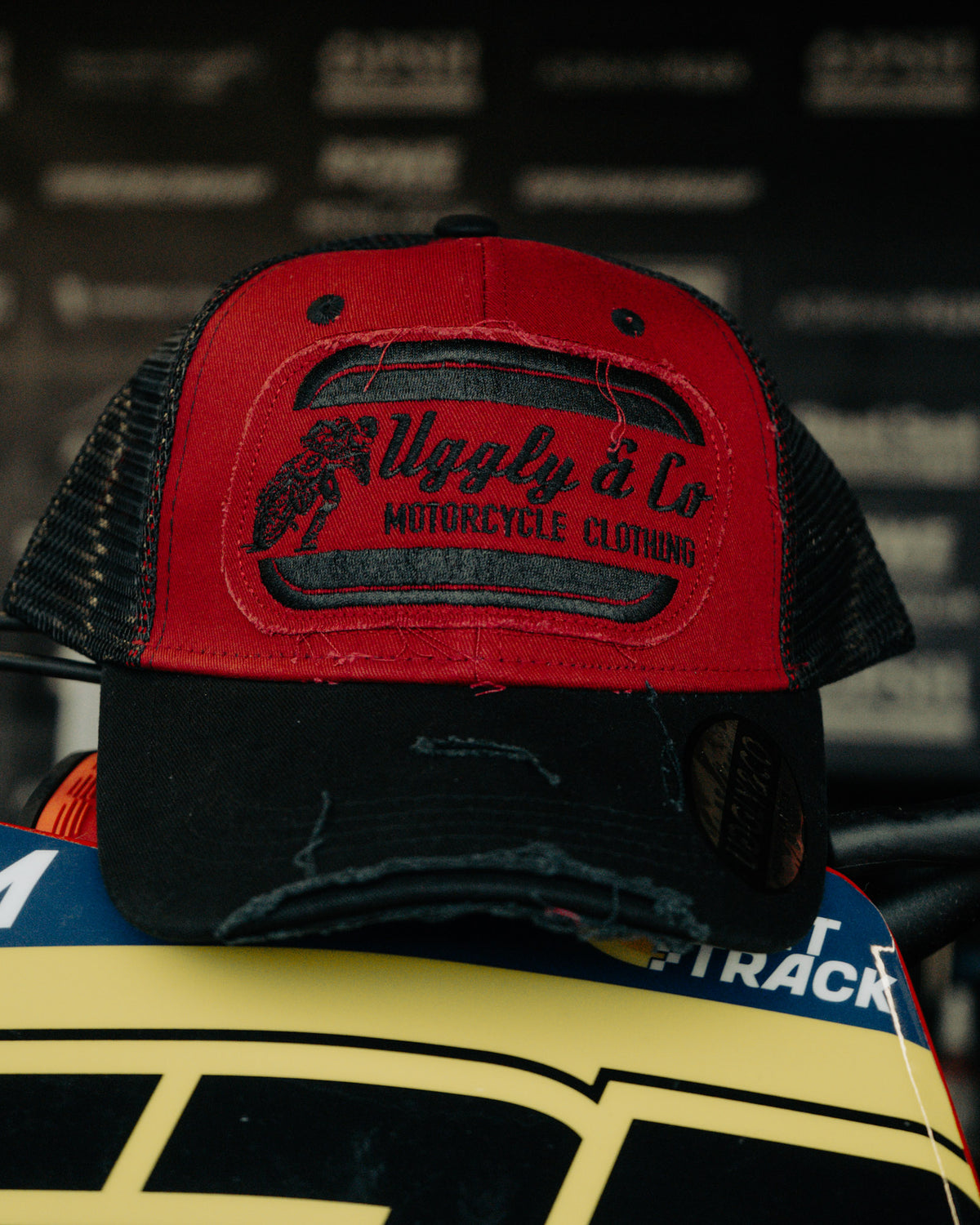 Black & Red Flat Track Trucker Hat shown from the front, featuring bold Uggly&Co branding, red detailing and a vintage racing-inspired trucker fit.