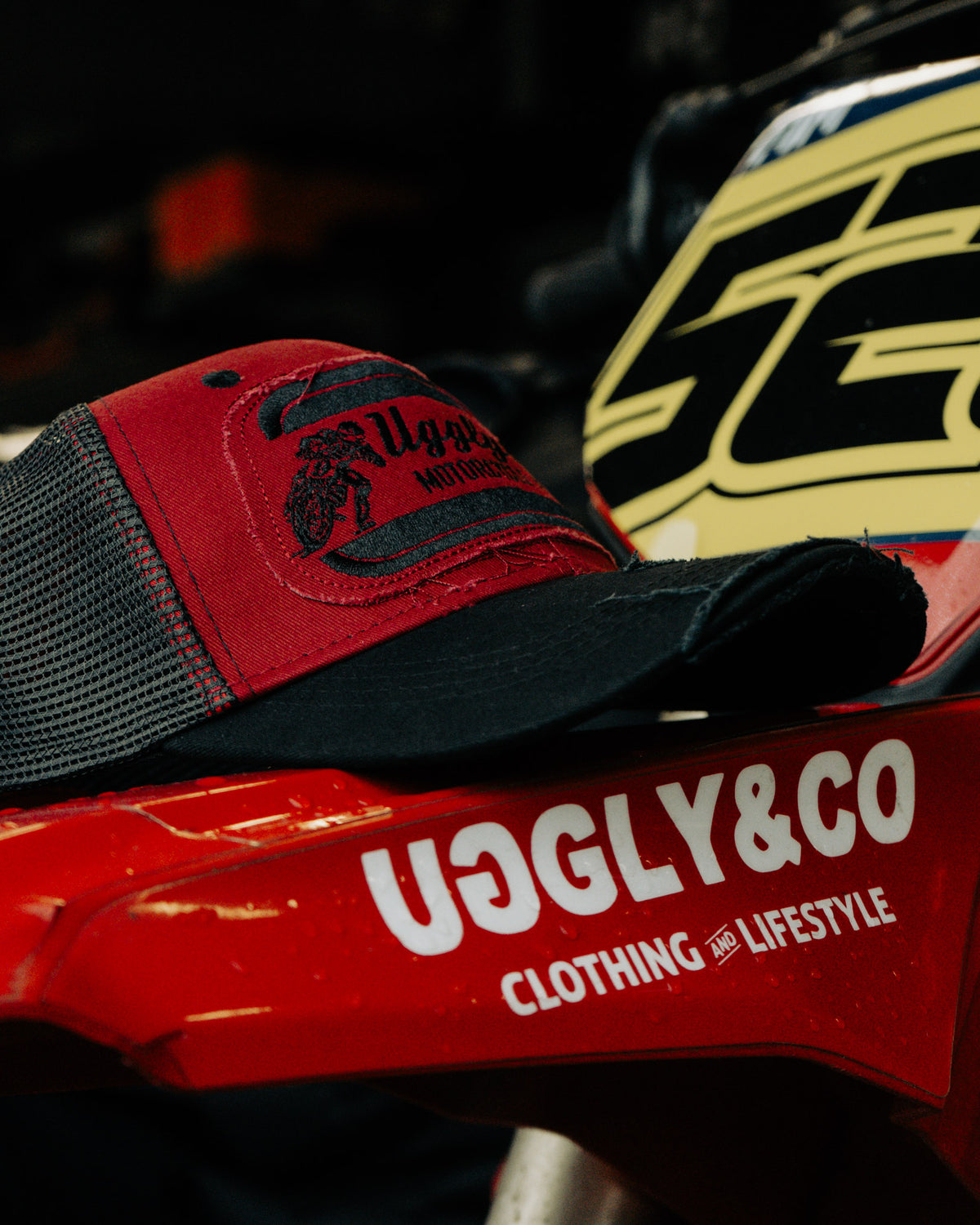 Side view of the Black & Red Flat Track Trucker Hat showing the mesh back, curved peak and motorsport-inspired patch details.