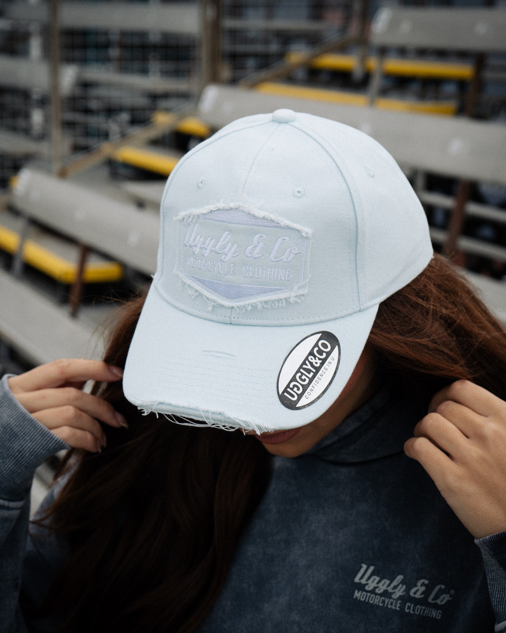 close up shot of a girl in a baby blue hat and blue acid wash hoodie