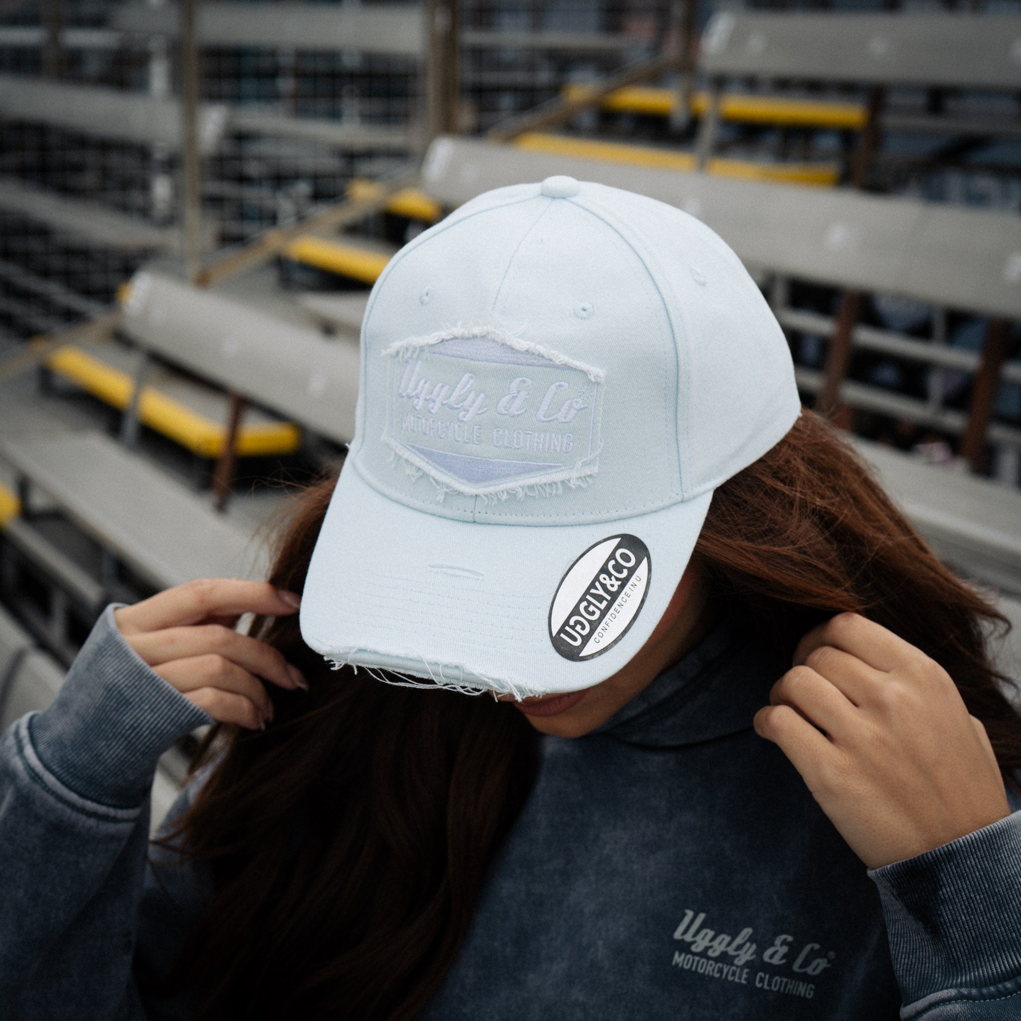 close up shot of a girl in a baby blue hat and blue acid wash hoodie