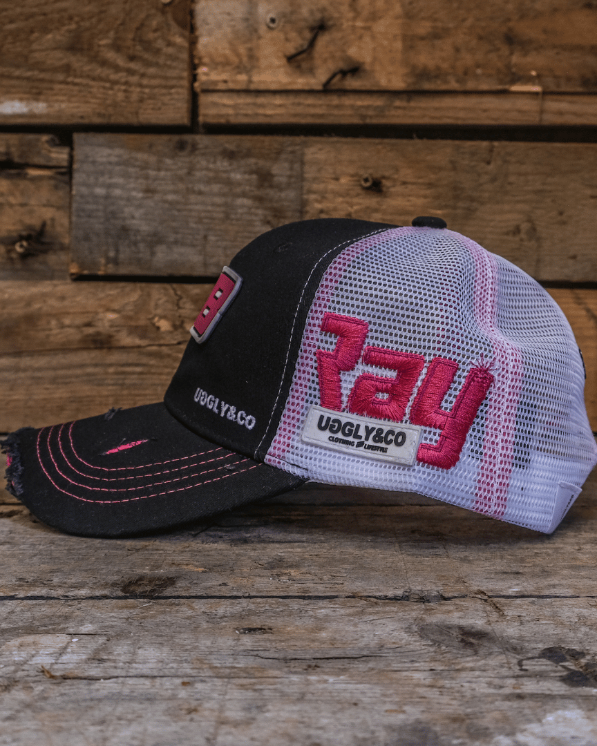 Side view of a trucker hat with number 28 on the front and 'Ray' and the Uggly&Co logo on the side in front of a wooden background