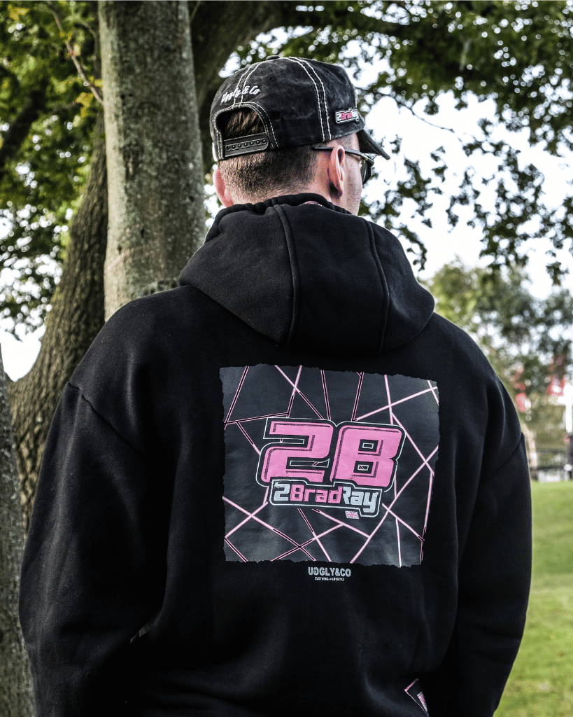 Person wearing a black hoodie with a graphic design on the back, standing outdoors.