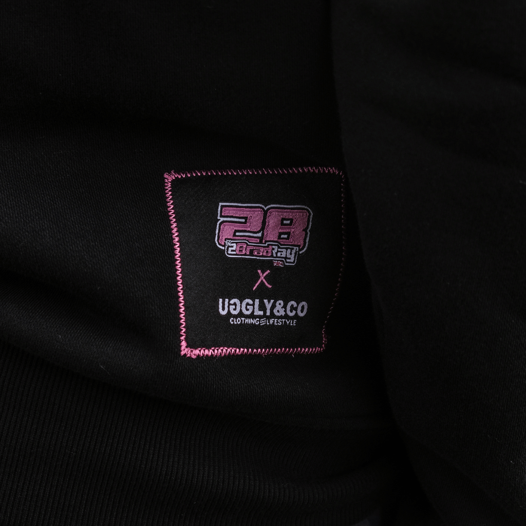 Close-up of a black garment with a brand label featuring '28' and 'UGLY&CO'.