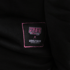 Close-up of a black garment with a brand label featuring '28' and 'UGLY&CO'.