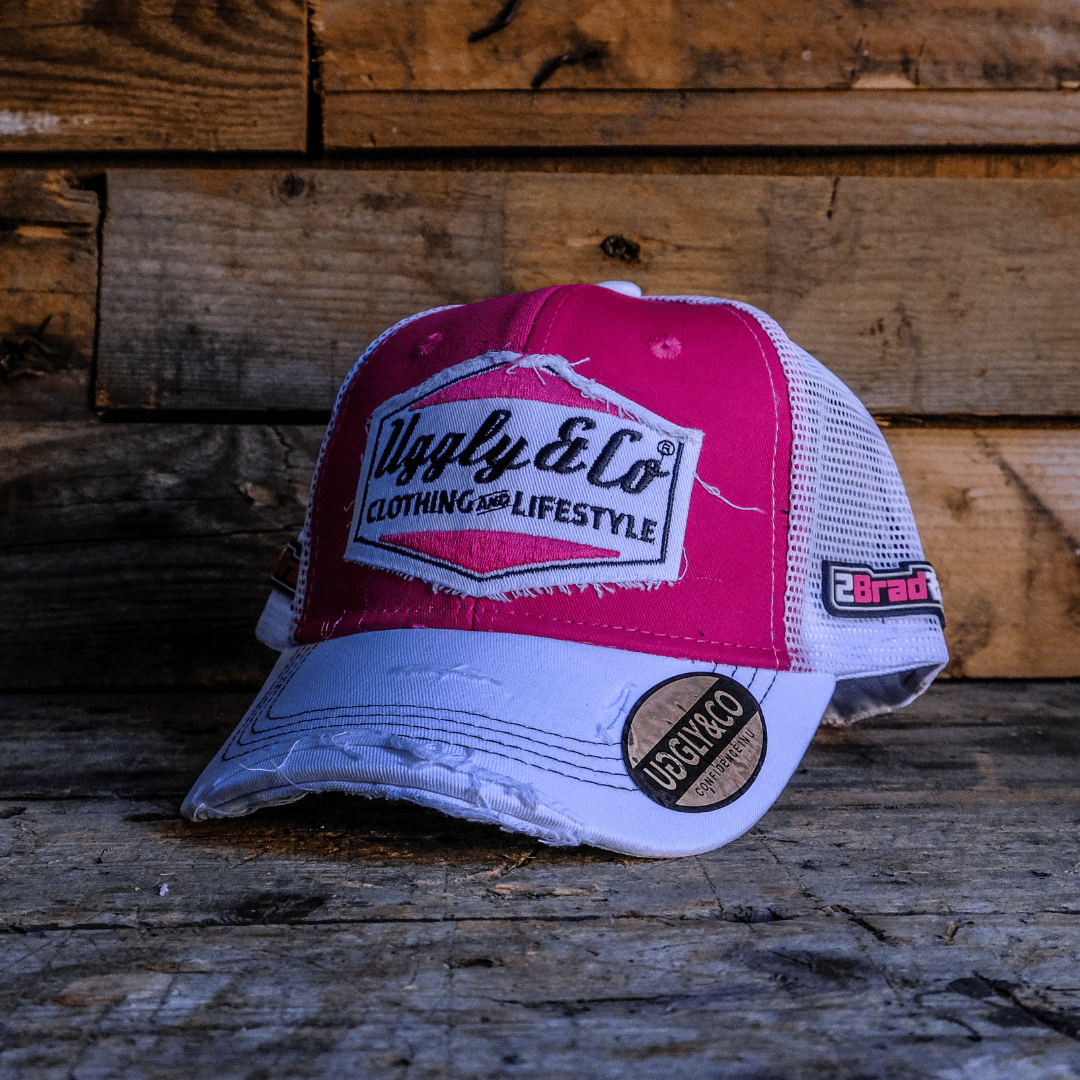 Bradley Ray branded pink and white cap with Uggly&Co diamond logo on the front on a wooden background