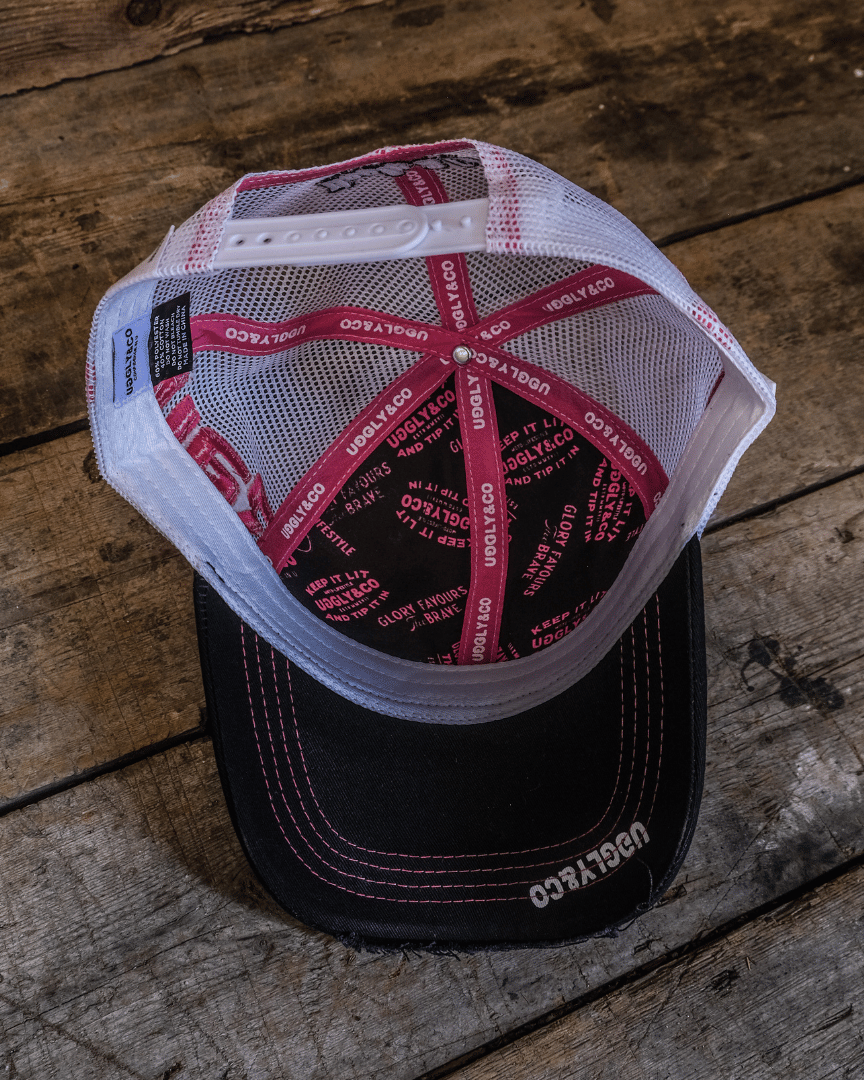 Inside view of a trucker hat with Uggly&Co branding on the seams in front of a wooden background