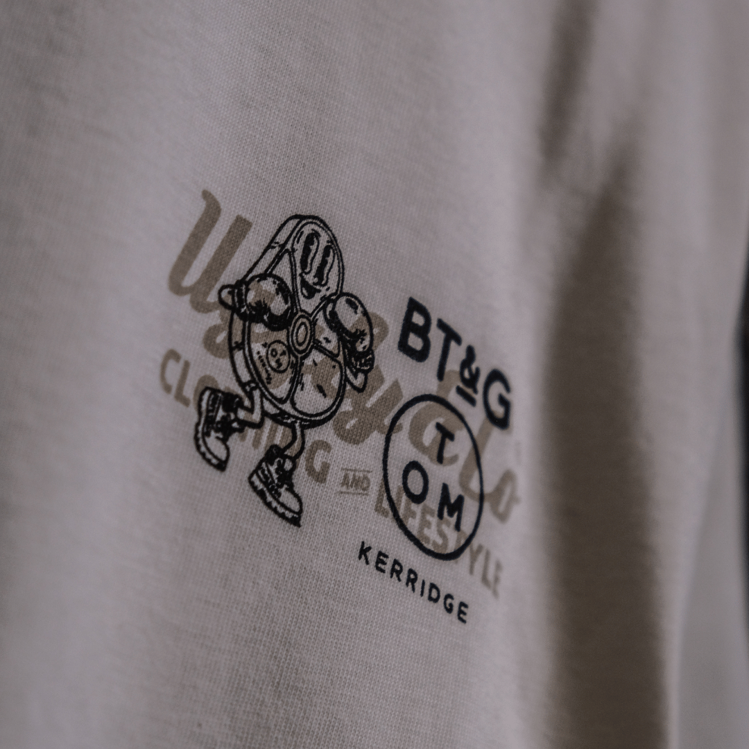 Close up view of the chest logo on a Tom Kerridge's Butchers Tap and Grill white t-shirt with black graphics and text