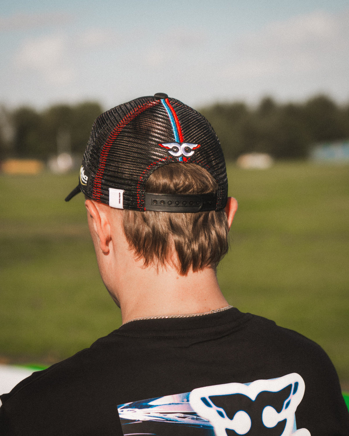 Close-up of the Carl Cox Trucker Hat collaboration design featuring Alpha Racing and Simon Reid branding, part of the Uggly & Co motorcycle lifestyle collection.