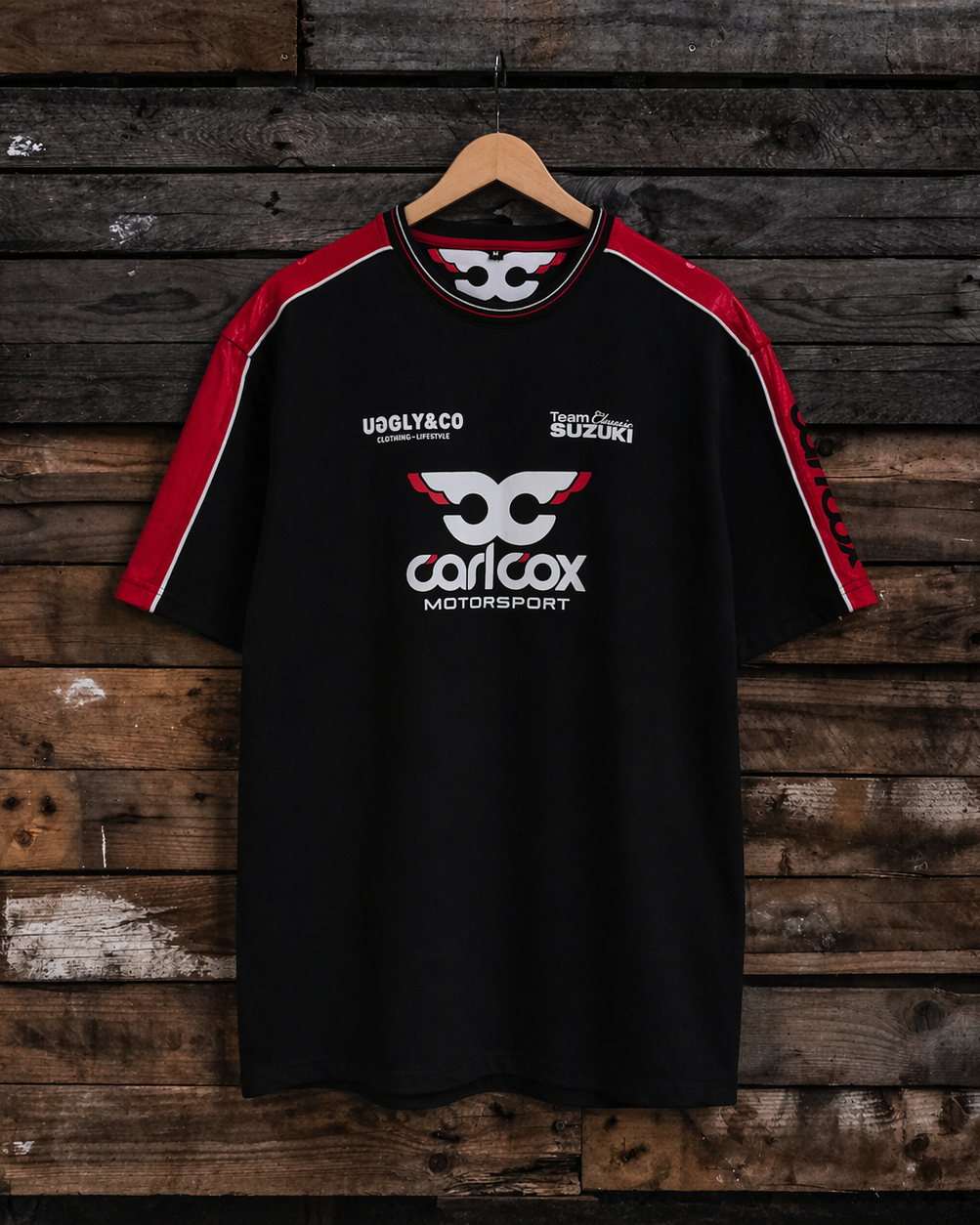 Front view of a Carl Cox motorsport and Team Classic Suzuki black and red t-shirt on a wood background