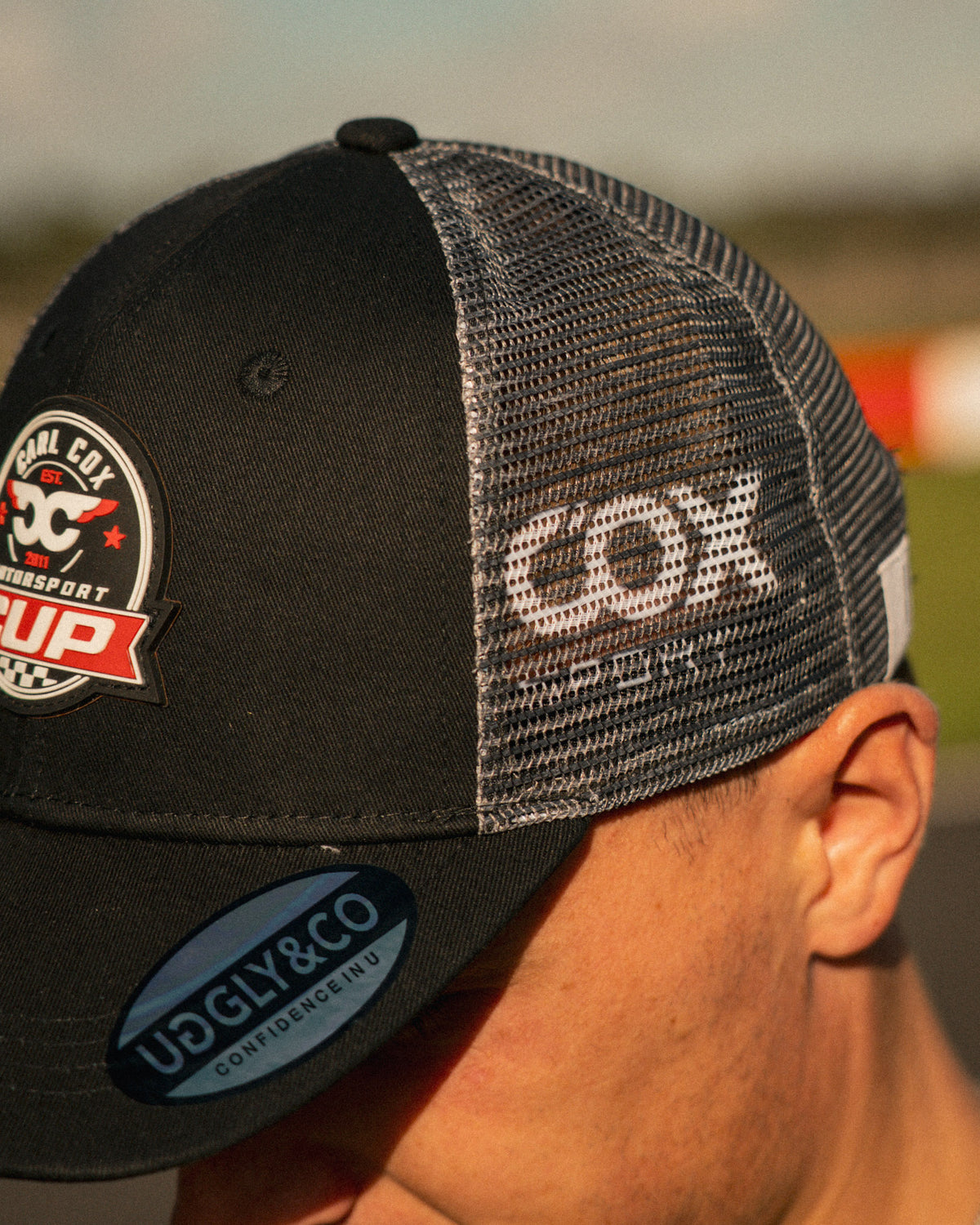 Side profile of the Carl Cox Motorsport Cup Cap, showcasing its curved peak and classic racing cap silhouette from the Uggly & Co motorsport collection.