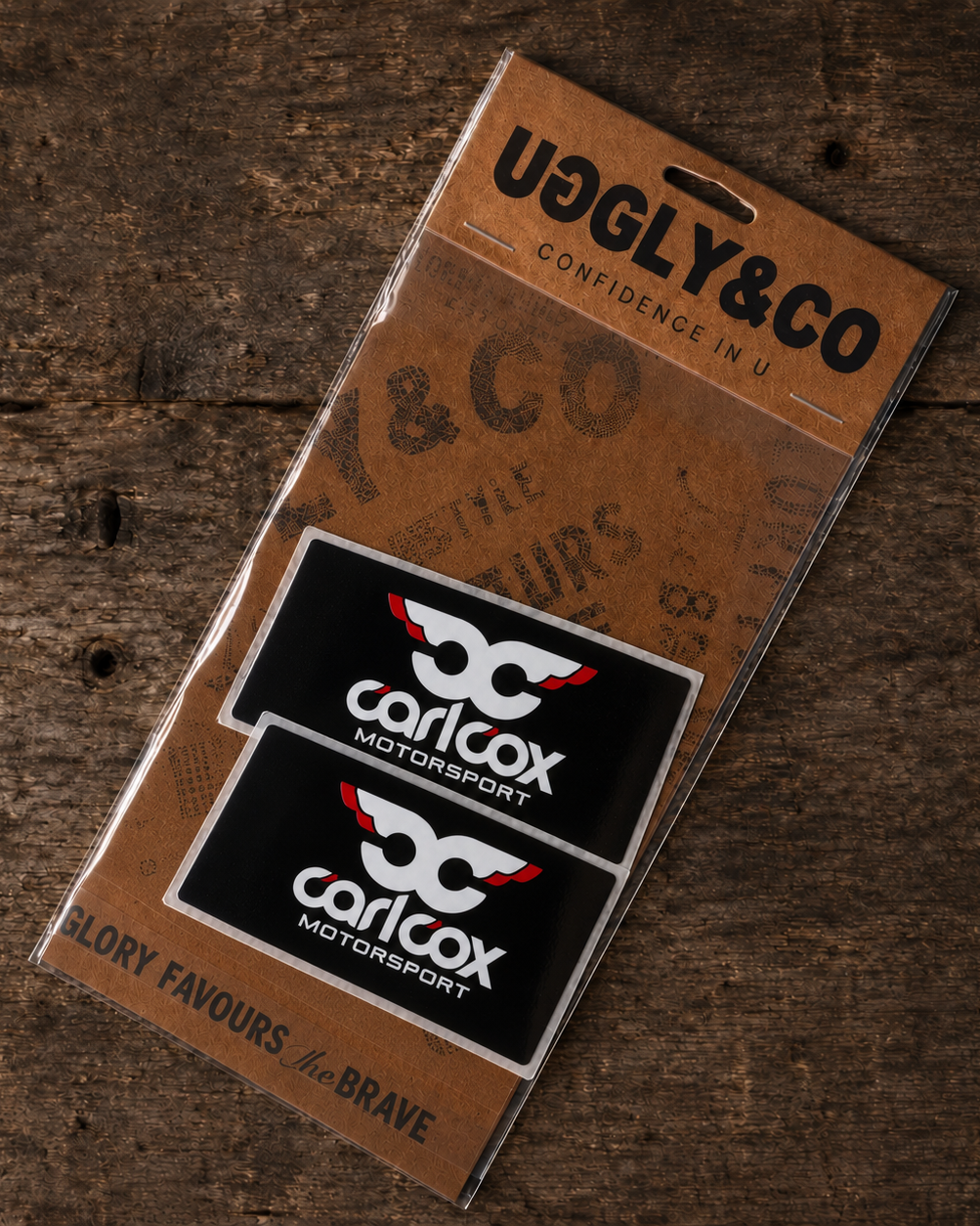 Carl Cox Motorsport sticker pack featuring two black rectangular stickers with white and red logo artwork in Uggly & Co packaging.
