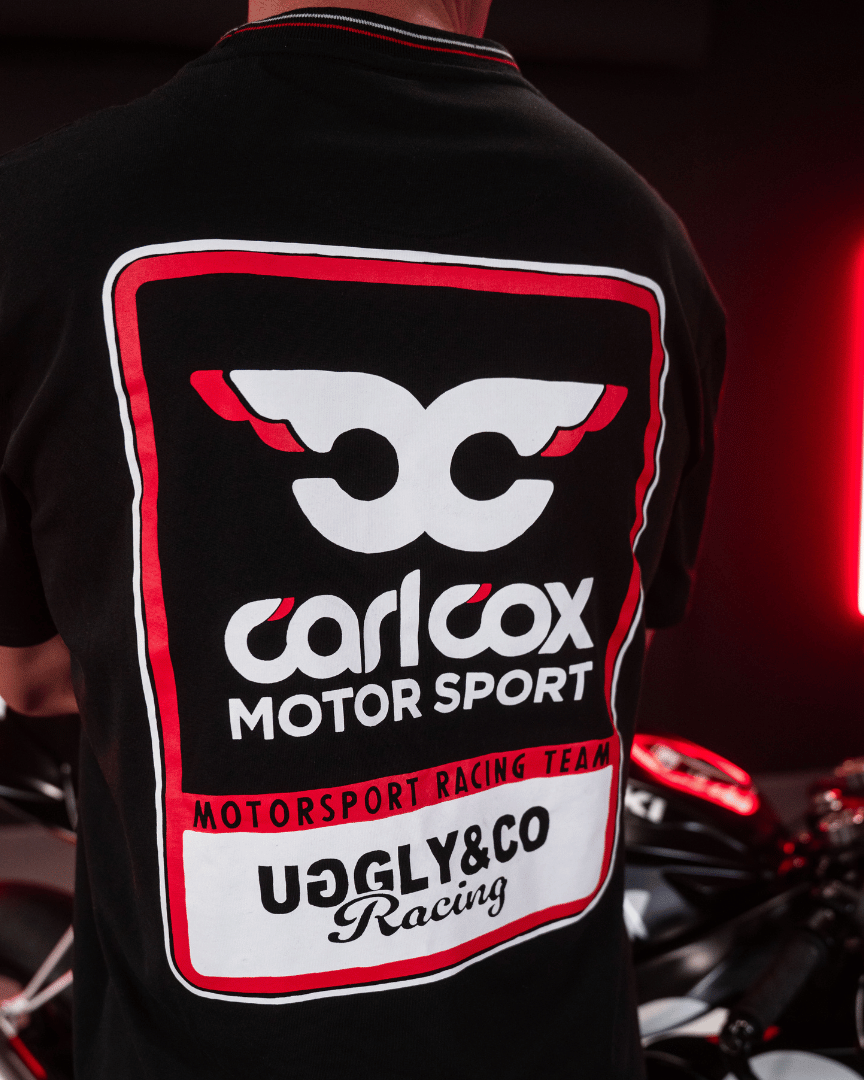 Close up of the detailing on the back of a Carl Cox motorsport black t-shirt with an Uggly&Co logo and a motorcycle behind
