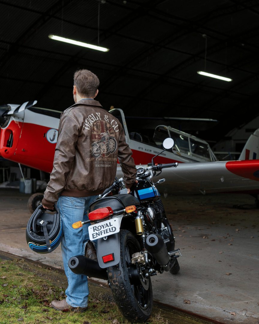 Man standing next to a motorcycle with a red and white airplane in the background