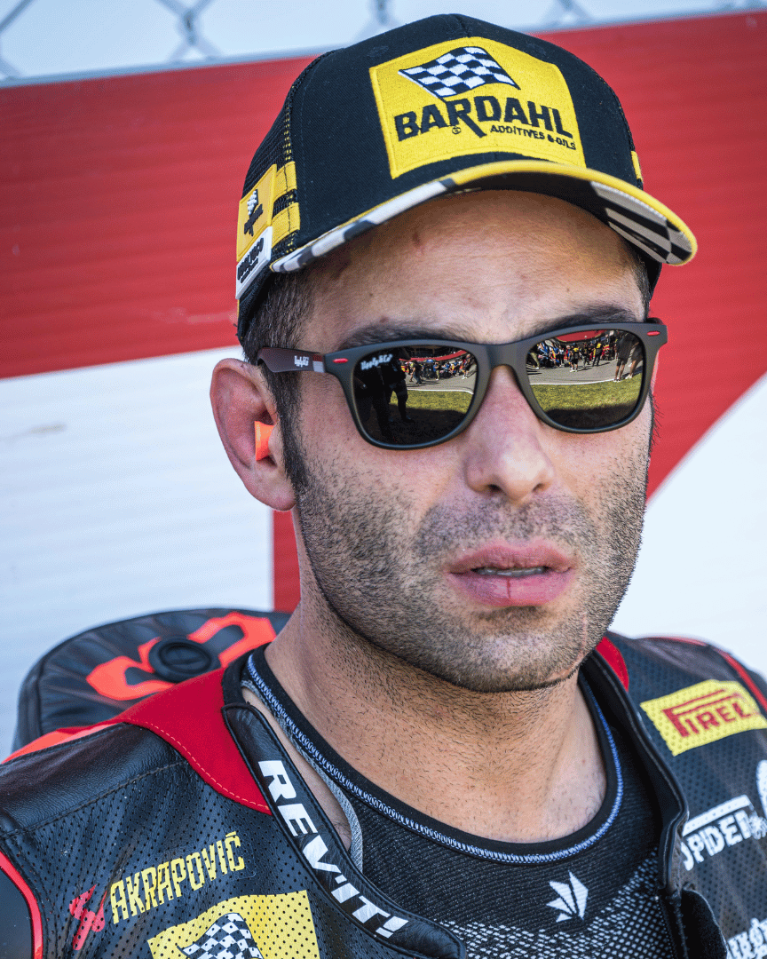 Danilo Pertrucci wearing sunglasses and a yellow and black Uggly&Co Bardahl Danilo Pertrucci #9 merchandise trucker hat
