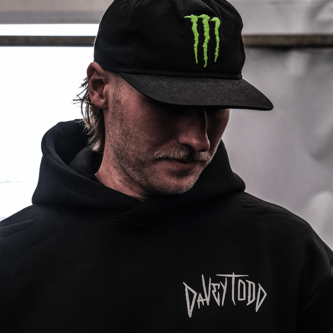Person wearing a black hoodie with 'Davy Todd' logo and a black cap with a green logo.
