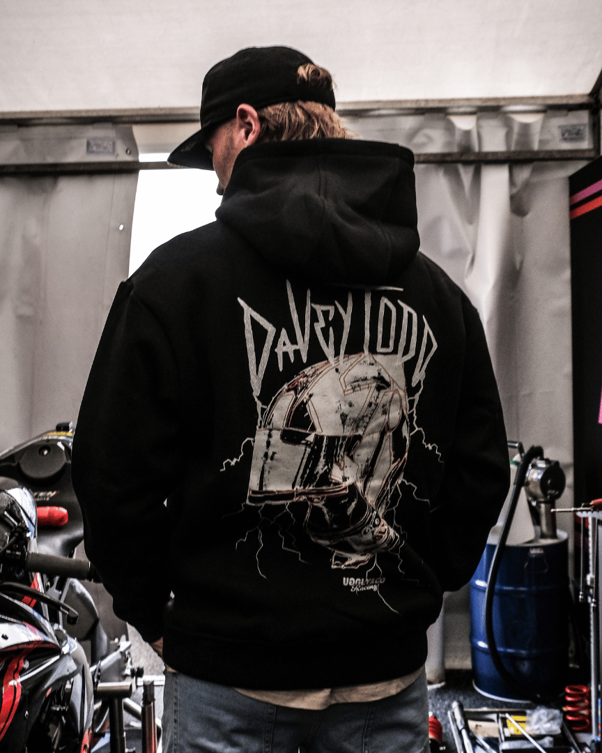 Davey Todd, Road Racer wearing a black hoodie with a graphic design in a garage setting