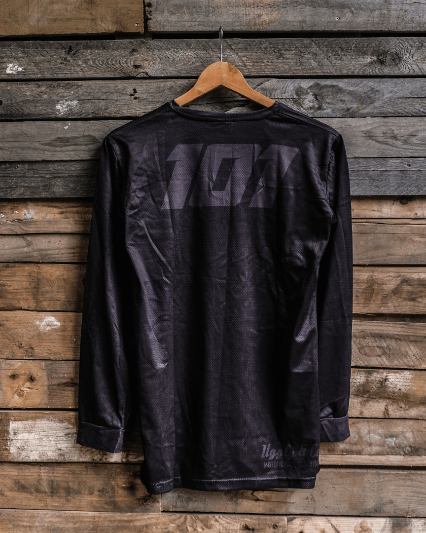 A black long-sleeved David Knight Motocross jersey hanging on a wooden hanger against a wooden background with 101 print.