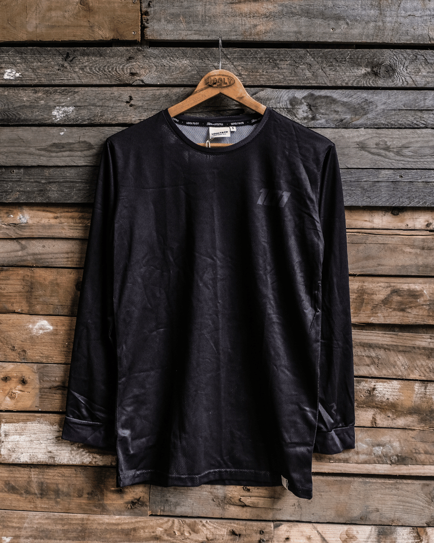 Front view of a black long-sleeved David Knight Motocross jersey hanging on a wooden hanger against a wooden background with 101 print.