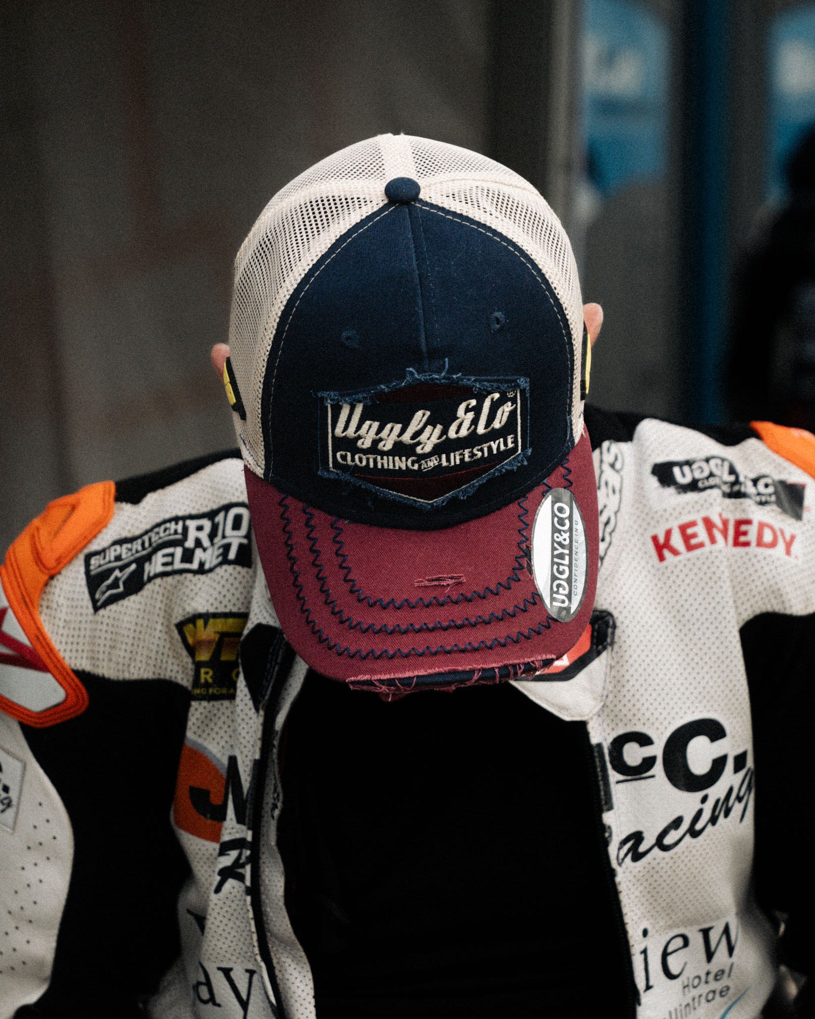 Jeremy McWilliams in red, white and blue trucker hat stood in pit lane with head down