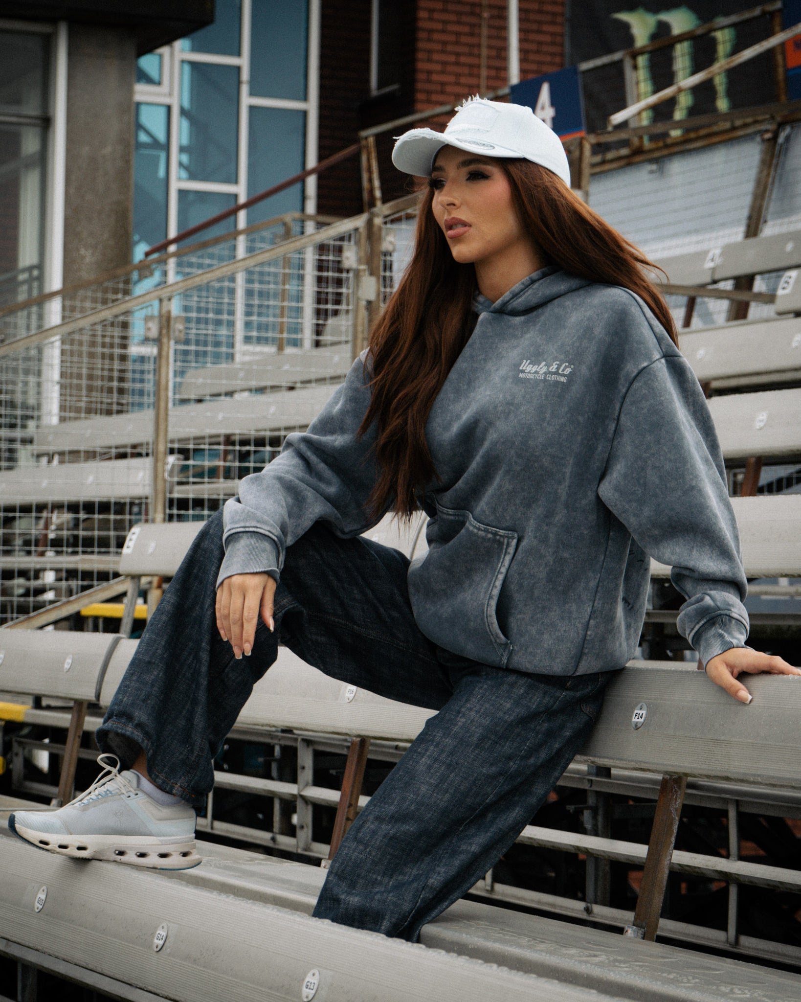 Female model wearing a blue acid wash hoodie in a casual lifestyle setting.
