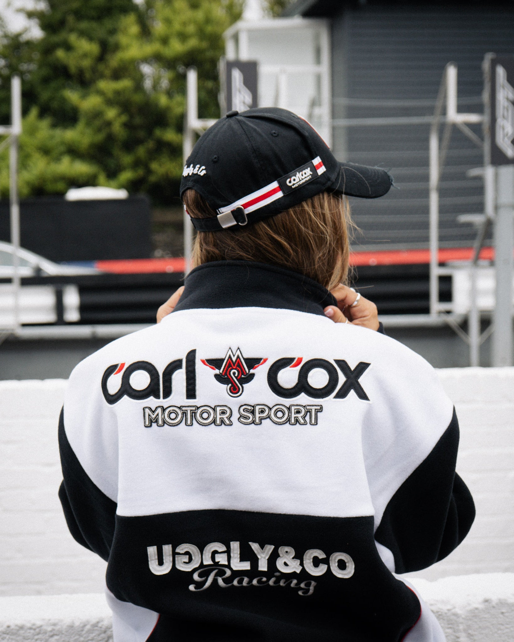 Female model wearing a Carl Cox Motorsport racing jacket in the event paddock.
