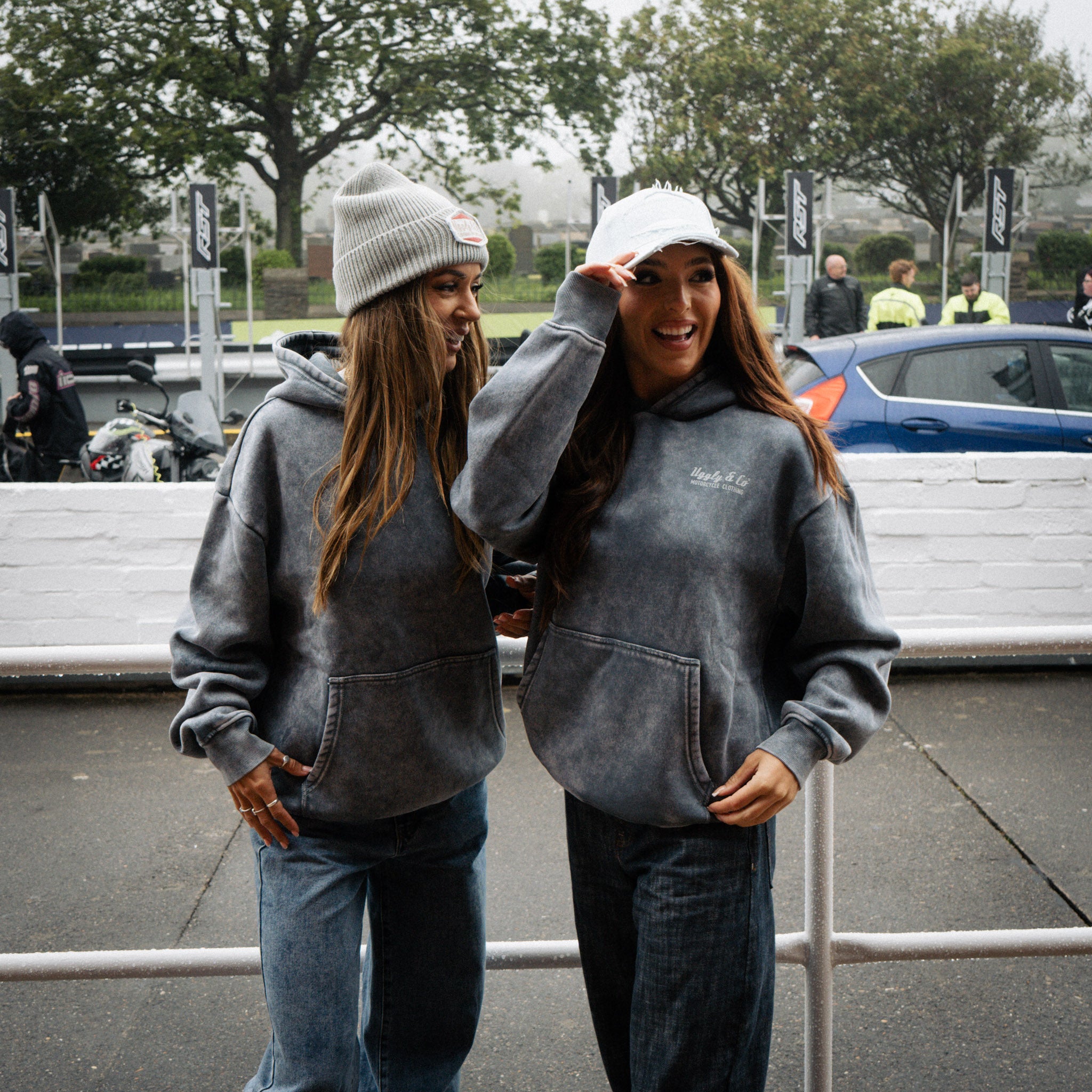 Female model wearing a blue acid wash hoodie, shown from the front at race event