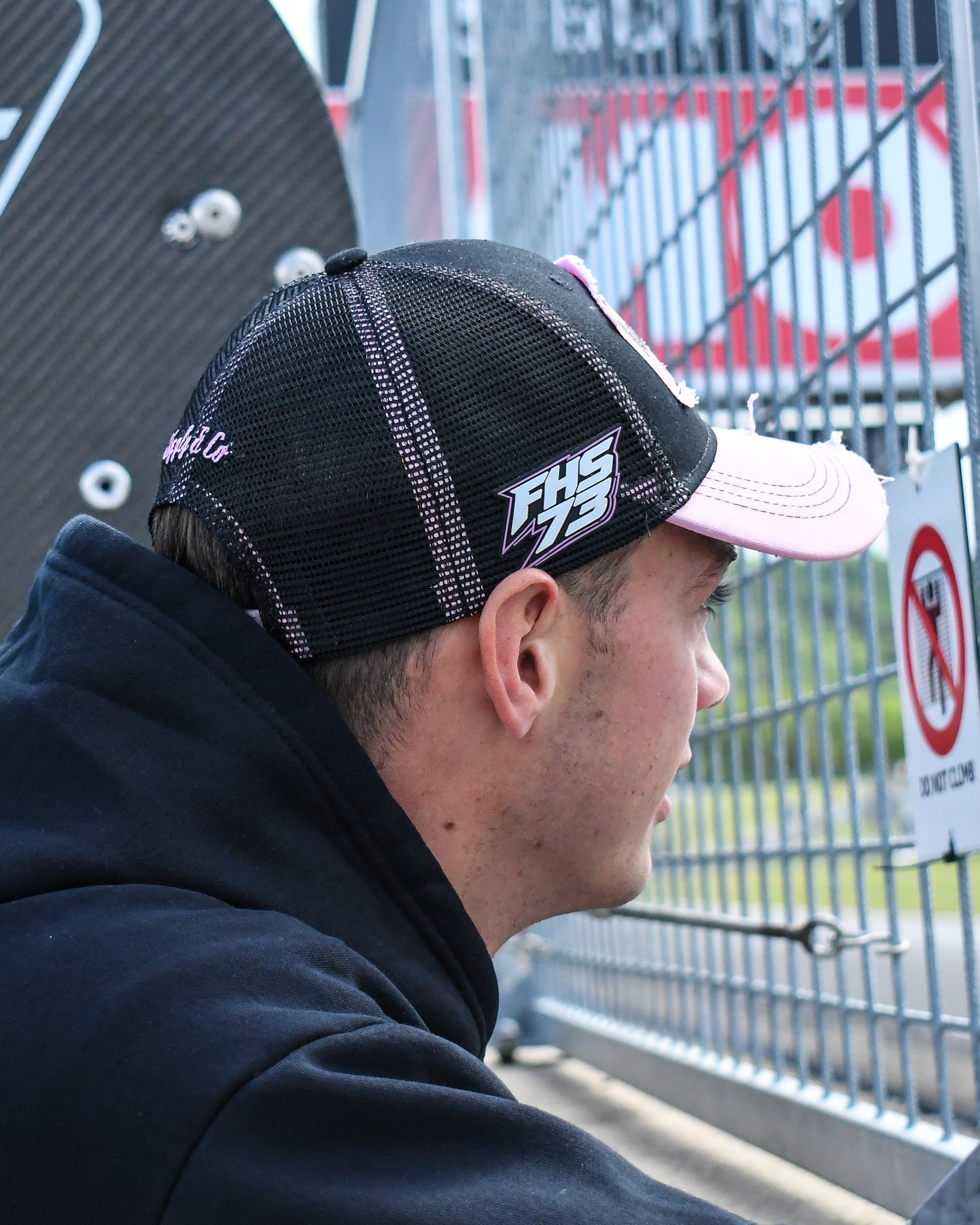 Close up side-profile image of Fenton Seabright in a black and pink trucker cap during race day preparations