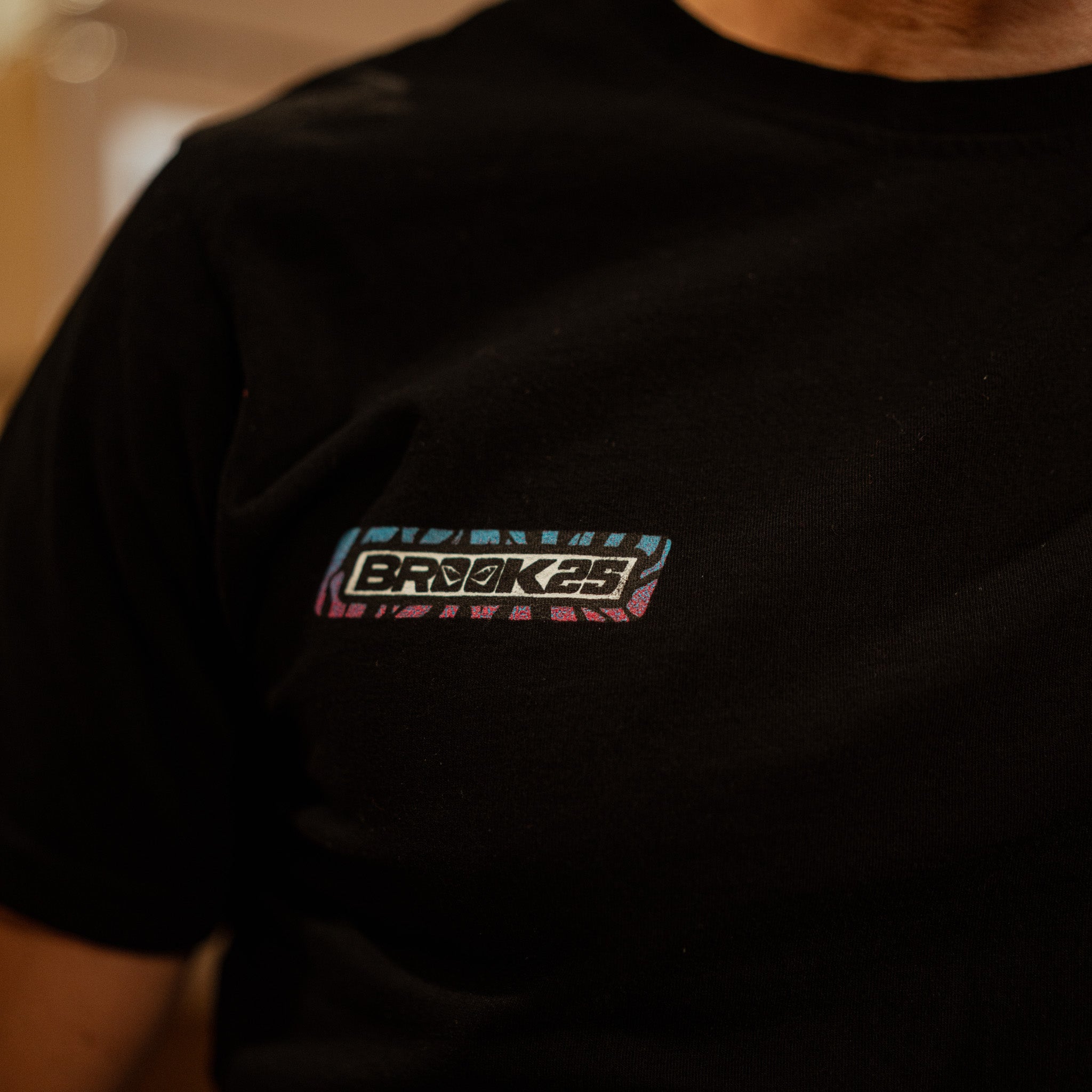 Close up view of a the left chest logo of a Josh Brookes signature diamond black t-shirt and a blurred background