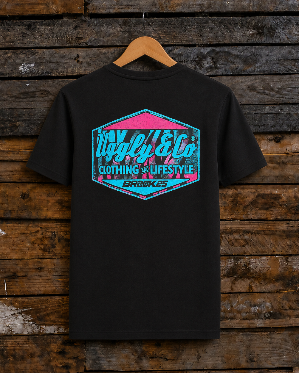 Rear view of a Josh Brookes signature diamond black t-shirt with blue Uggly&Co logo on a wooden background
