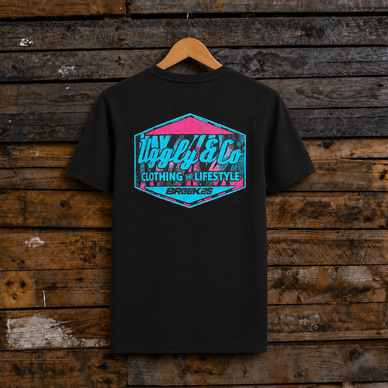 Rear view of a Josh Brookes signature diamond black t-shirt with blue Uggly&Co logo on a wooden background