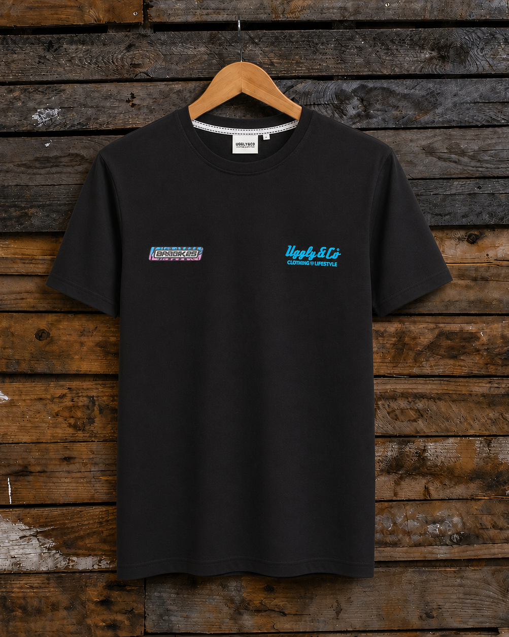 Front view of a Josh Brookes signature diamond black t-shirt with blue Uggly&Co logo on a wooden background