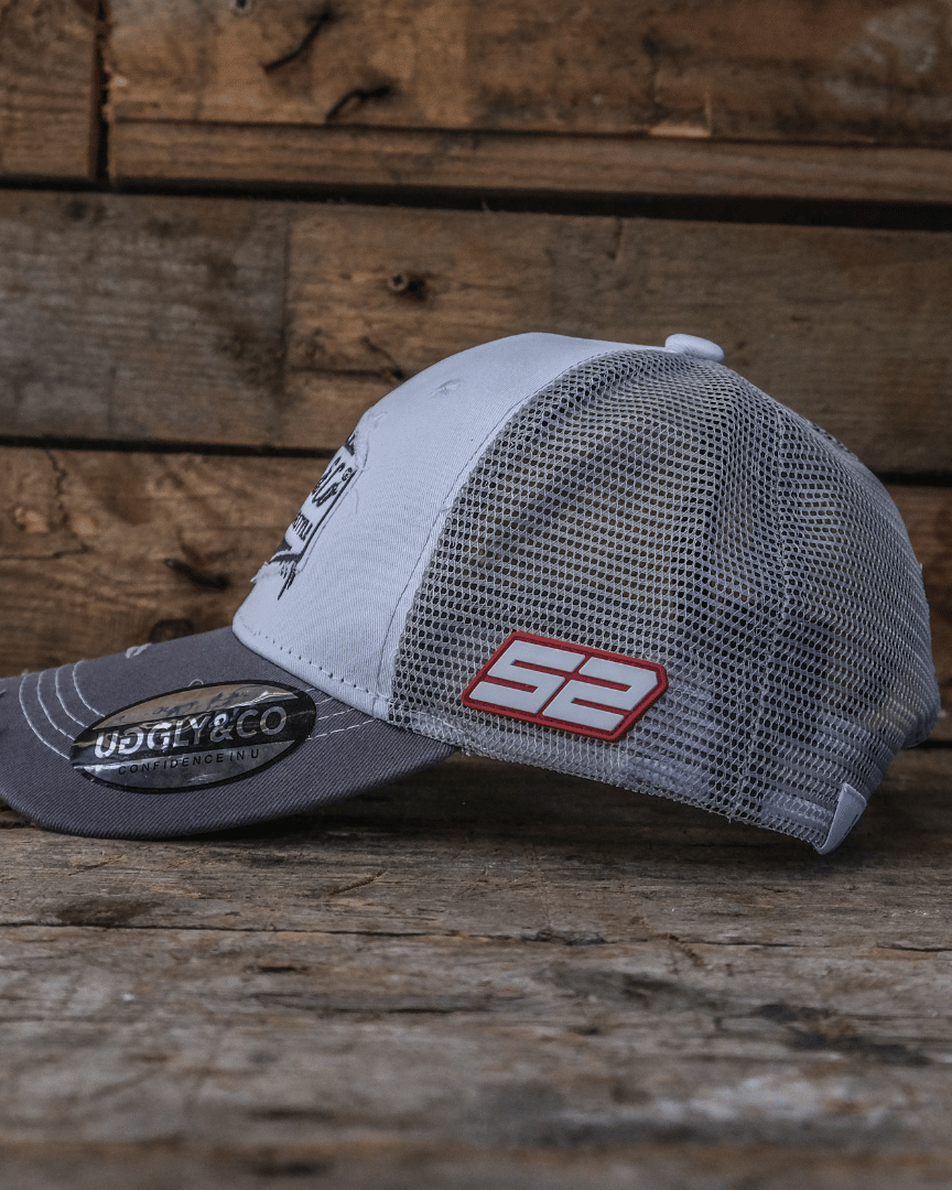 Grey and black trucker hat side view with mesh back and 52 on the side on a wooden surface