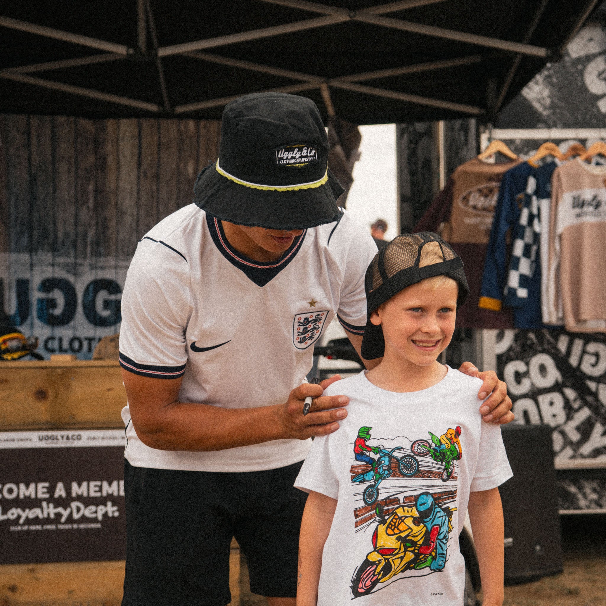 Kyle Ryde in his black bucket hat with young motorsport fan in uggly and co merch