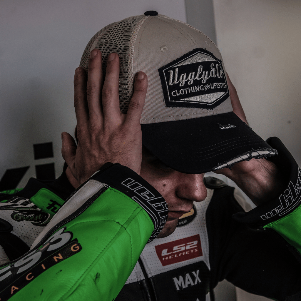 Max Cook wearing a trucker hat with an Uggly&Co brand logo, in his racing leathers