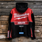 A Milwaukee Tools x DUCATI teamwear hoodie with red and black color scheme, featuring the DUCATI logo and official 2025 Uggly&Co collaboration branding, displayed on a wooden background.
