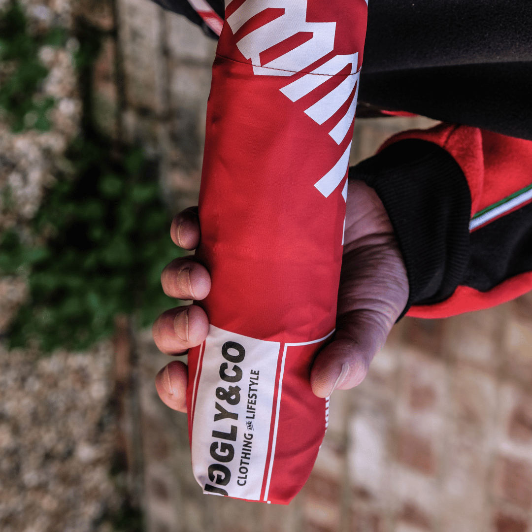 A model holding a Milwaukee Tools x Ducati umbrella in it's packing sleeve, featuring the Milwaukee Tools logo, Ducati logo, and the Uggly&Co logo