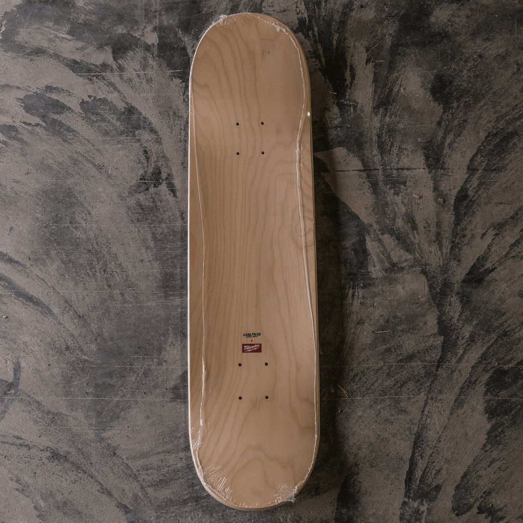 Wooden skateboard deck on a textured gray surface