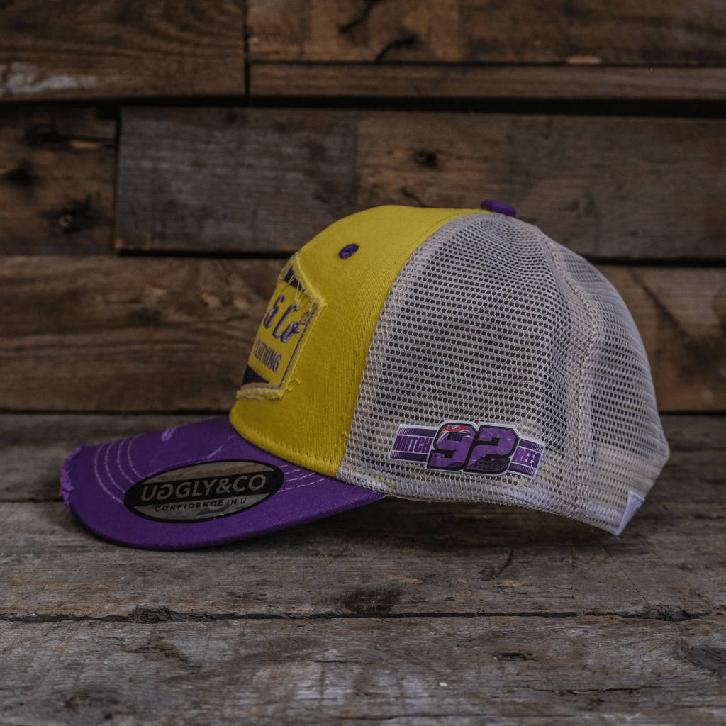 Side view of a yellow and purple trucker hat with a white mesh back, featuring the Uggly & Co Motorcycle Clothing logo on the front and 92 logo on the side