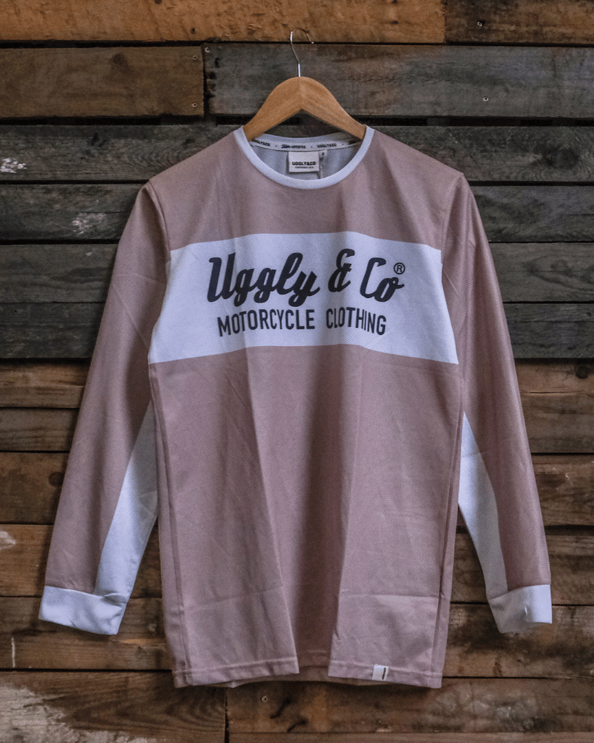 Brown long-sleeve motocross jersey with 'Uggly & Co Motorcycle Clothing' logo on a wooden background