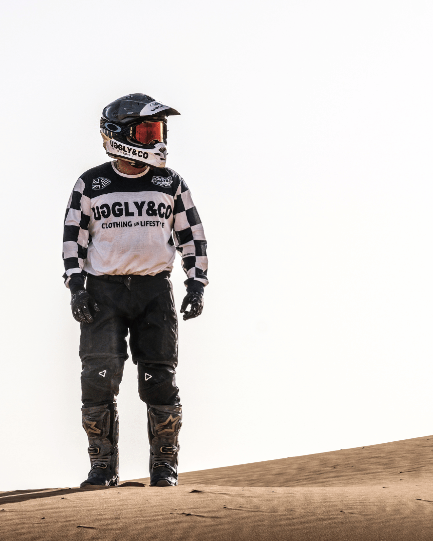 Motocross rider in full gear standing in the desert wearing a chequered Uggly&Co MX shirt